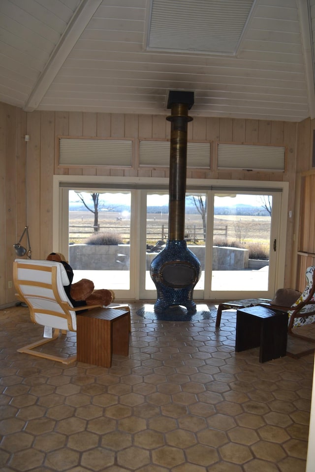 living area featuring lofted ceiling with beams, wood walls, and a wood stove