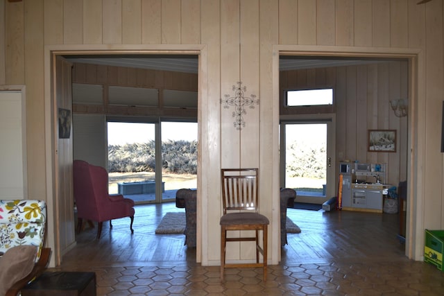 hall with a healthy amount of sunlight, wood walls, and dark tile patterned floors