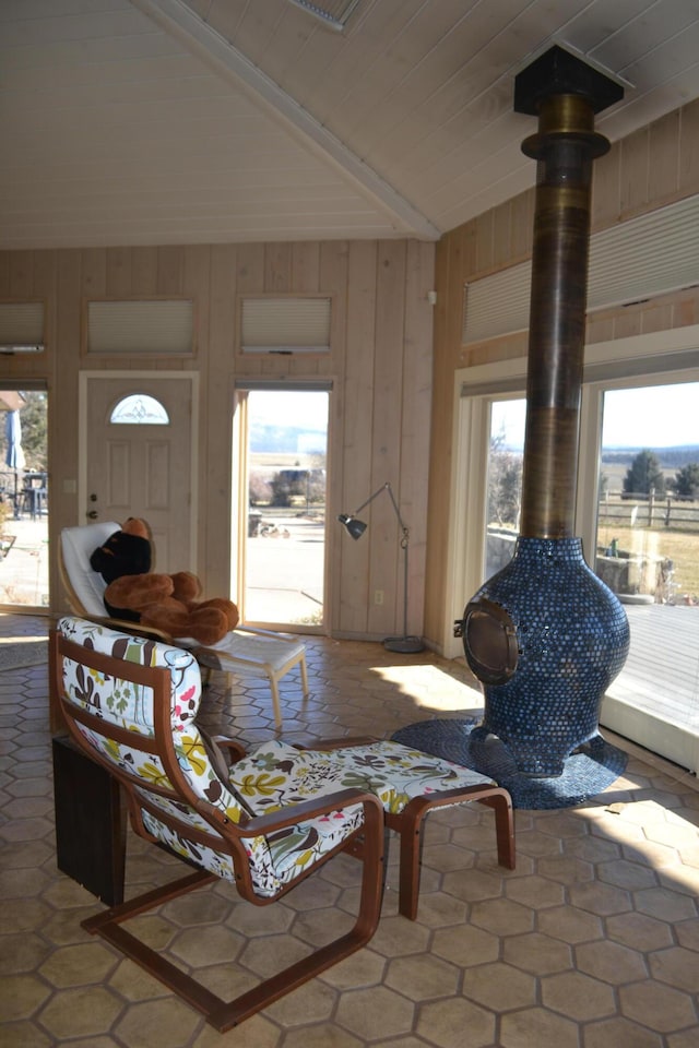 living room featuring a wood stove, wooden walls, and vaulted ceiling