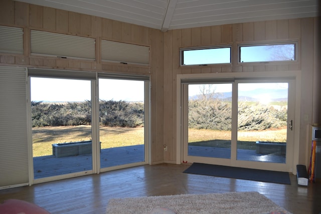 entryway featuring vaulted ceiling, hardwood / wood-style flooring, and wooden walls