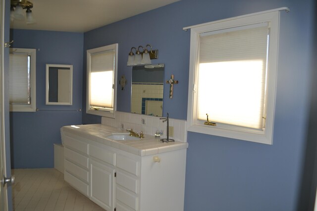 bathroom featuring decorative backsplash, plenty of natural light, vanity, and tile patterned flooring