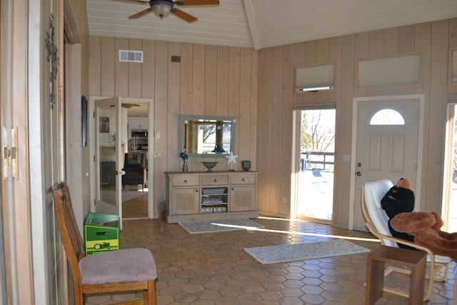 living room with lofted ceiling, ceiling fan, and wooden walls