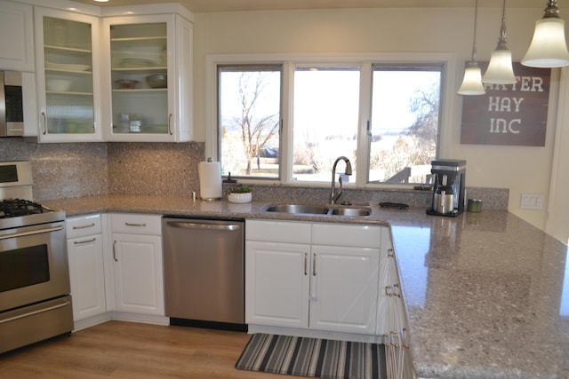 kitchen featuring sink, white cabinetry, hanging light fixtures, light stone countertops, and stainless steel appliances