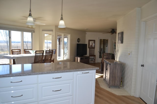 kitchen featuring decorative light fixtures, light hardwood / wood-style floors, white cabinets, and ceiling fan