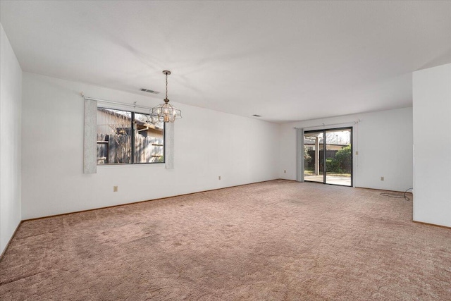 empty room featuring carpet and a notable chandelier