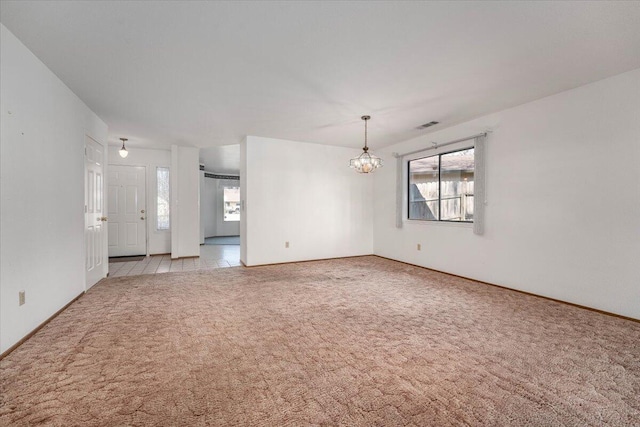 carpeted spare room with an inviting chandelier