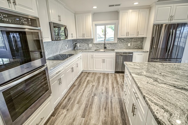 kitchen with light stone countertops, white cabinetry, sink, and stainless steel appliances