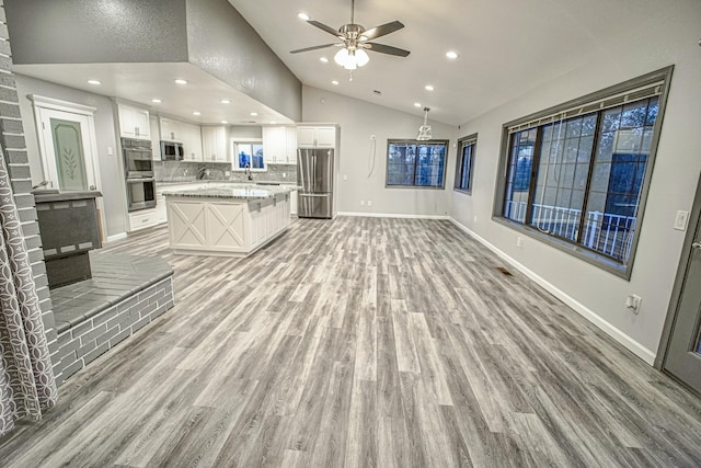 unfurnished living room with vaulted ceiling, ceiling fan, light hardwood / wood-style floors, and sink