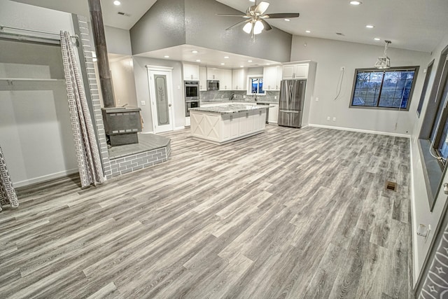 kitchen with a center island, decorative backsplash, white cabinetry, light hardwood / wood-style flooring, and appliances with stainless steel finishes