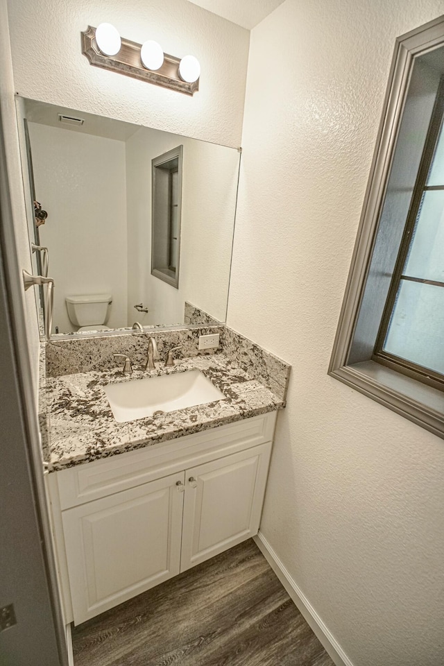 bathroom with toilet, wood-type flooring, and vanity