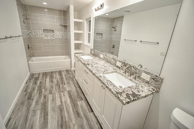 full bathroom featuring toilet, tiled shower / bath, hardwood / wood-style floors, and vanity