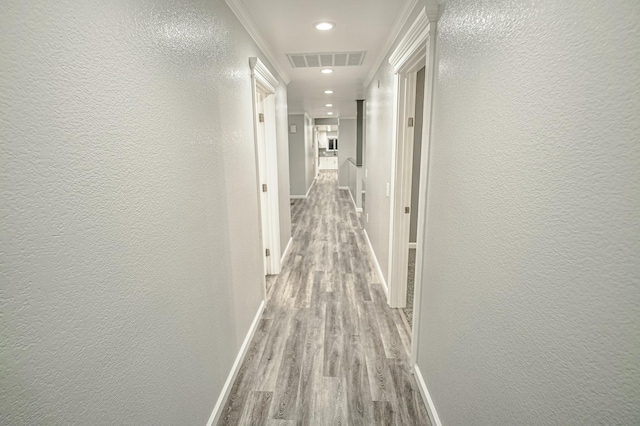 hallway with light hardwood / wood-style floors and crown molding