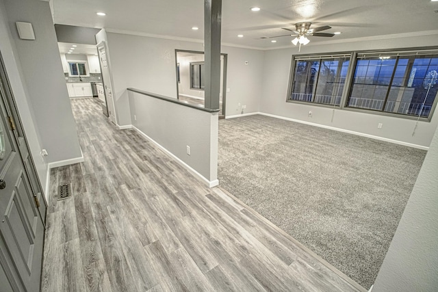 interior space with ceiling fan, light carpet, and ornamental molding