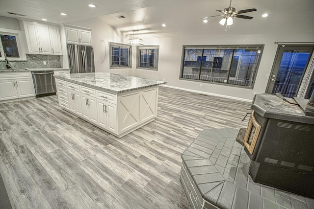 kitchen featuring appliances with stainless steel finishes, a kitchen island, white cabinetry, sink, and backsplash