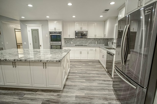 kitchen with black appliances, backsplash, light stone countertops, and white cabinetry