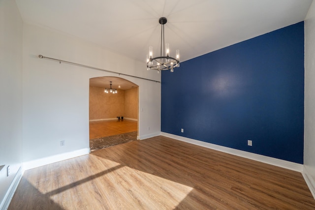 unfurnished room with a chandelier and hardwood / wood-style floors