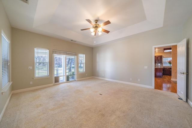 carpeted spare room featuring a tray ceiling and ceiling fan