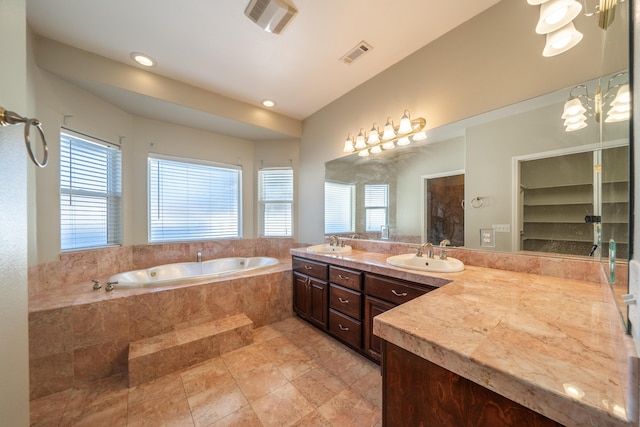 bathroom featuring vanity, a wealth of natural light, and tiled bath