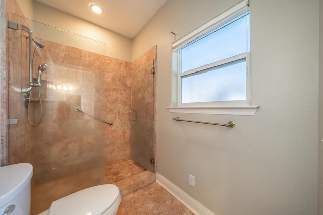 bathroom featuring a shower with shower door and toilet