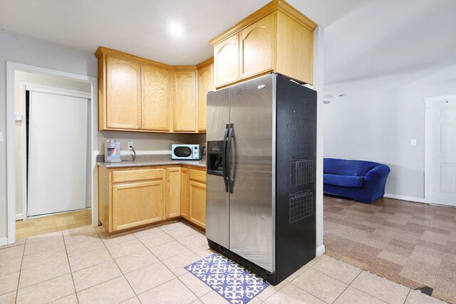kitchen featuring stainless steel fridge, light tile patterned flooring, and light brown cabinets