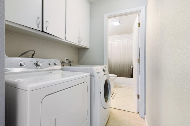 clothes washing area with cabinets, light tile patterned flooring, and washer and clothes dryer