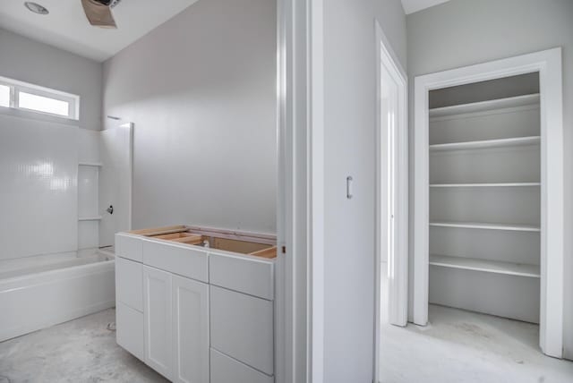 bathroom with tub / shower combination, vanity, and concrete flooring