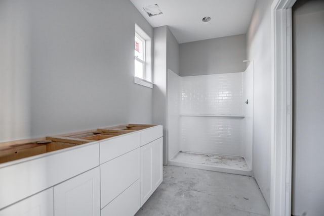 bathroom with a tile shower and concrete flooring