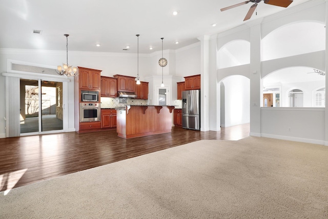 kitchen featuring appliances with stainless steel finishes, pendant lighting, decorative backsplash, dark colored carpet, and a center island