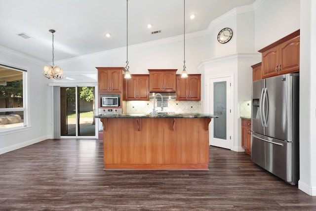 kitchen featuring hanging light fixtures, a center island with sink, a breakfast bar, and appliances with stainless steel finishes