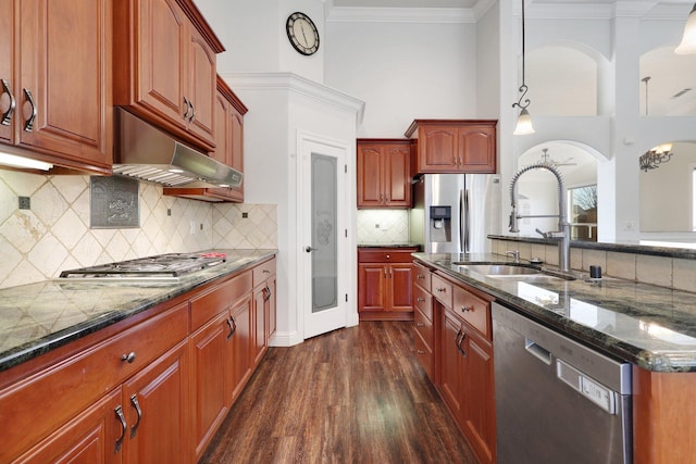 kitchen with sink, stainless steel appliances, dark hardwood / wood-style flooring, decorative light fixtures, and dark stone counters