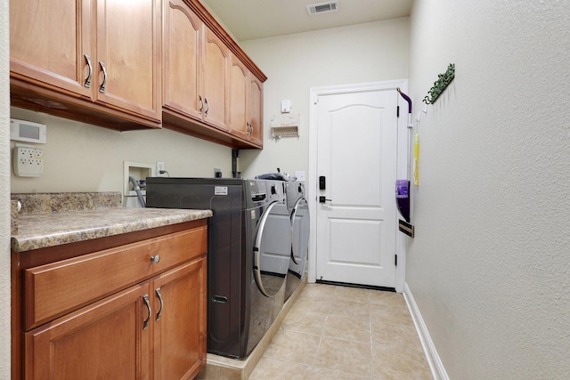 laundry area with cabinets, washing machine and clothes dryer, and light tile patterned flooring