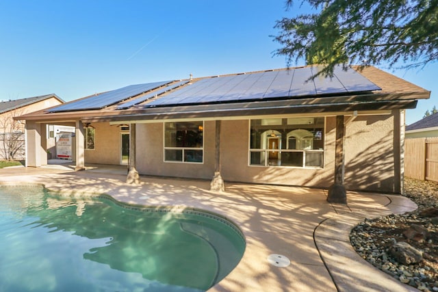 back of house featuring a fenced in pool, a patio, and solar panels