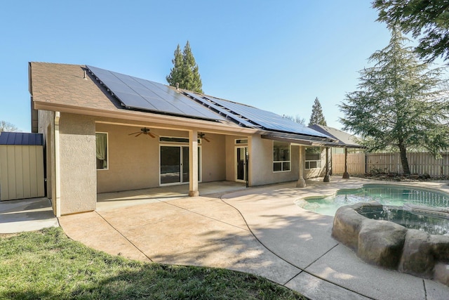 back of property with ceiling fan, a fenced in pool, a patio, and solar panels