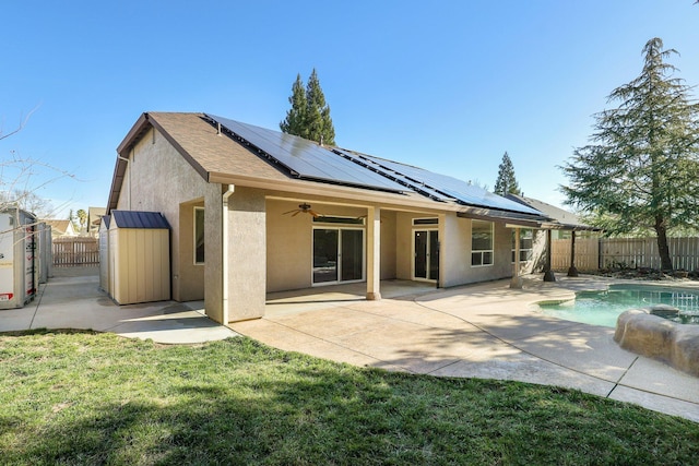 back of house featuring a fenced in pool, a yard, a patio, and solar panels