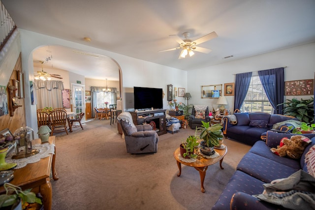 carpeted living room with ceiling fan with notable chandelier and plenty of natural light