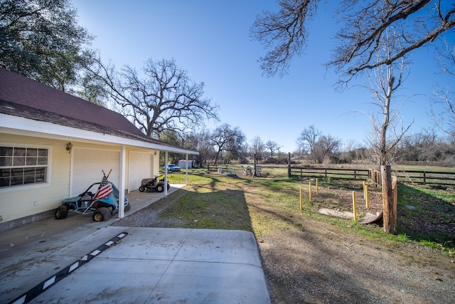 view of yard featuring an outbuilding, a garage, and a rural view