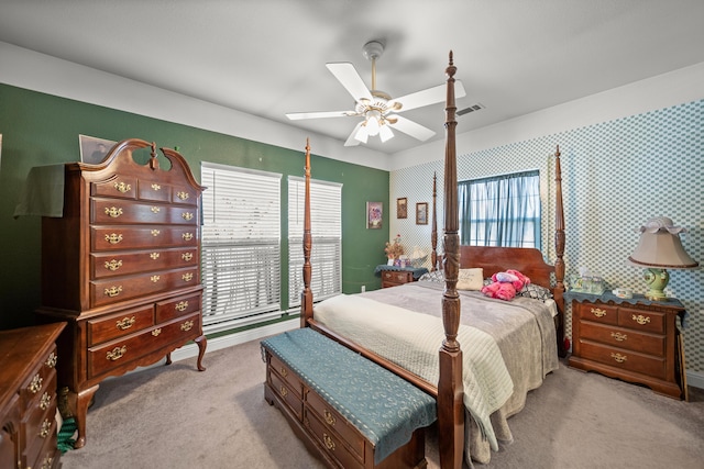 bedroom featuring ceiling fan, multiple windows, and light carpet