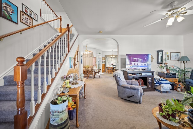 carpeted living room featuring ceiling fan with notable chandelier