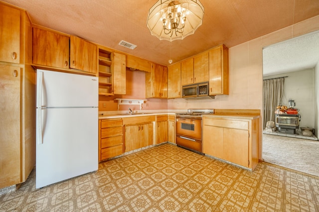 kitchen featuring white refrigerator, sink, an inviting chandelier, and stove