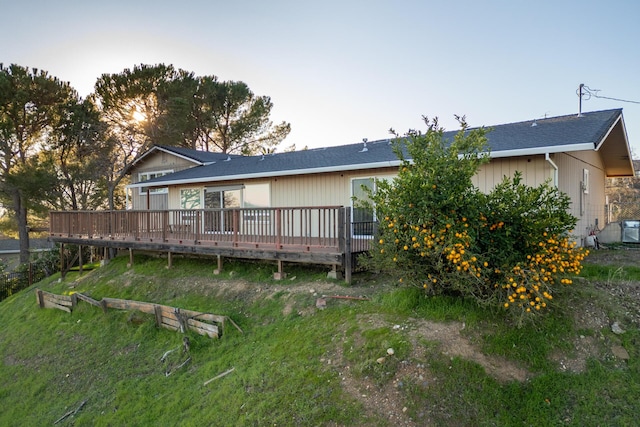 rear view of property featuring a wooden deck and a yard