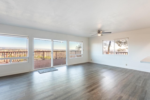 empty room featuring plenty of natural light, dark wood-type flooring, and ceiling fan