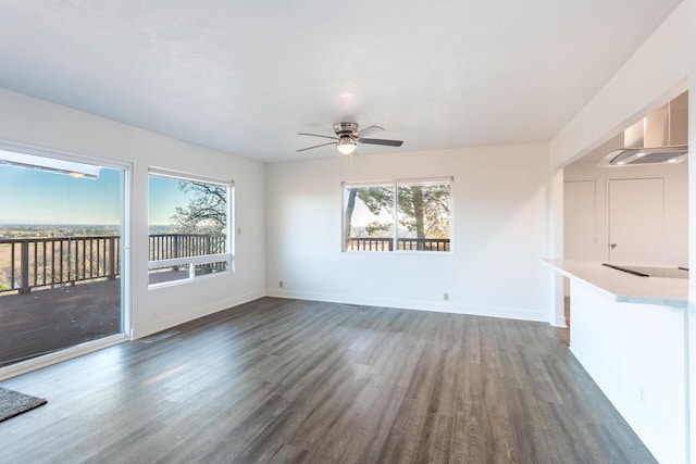 unfurnished living room with ceiling fan, a wealth of natural light, and dark hardwood / wood-style flooring