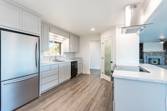 kitchen with sink, white cabinets, island range hood, and stainless steel refrigerator