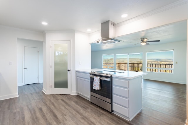 kitchen with stainless steel electric range oven, island range hood, white cabinets, light hardwood / wood-style flooring, and ornamental molding