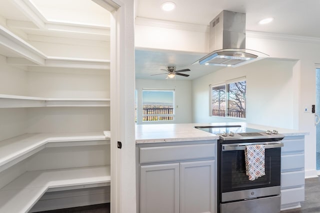 kitchen with crown molding, ceiling fan, dark hardwood / wood-style flooring, island exhaust hood, and stainless steel range with electric cooktop