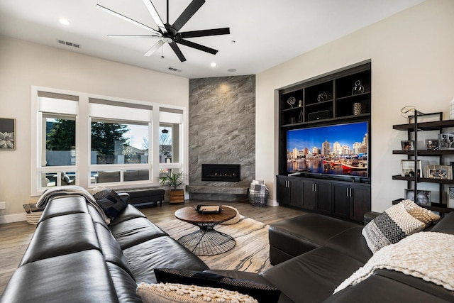 living room featuring ceiling fan, wood-type flooring, and a fireplace