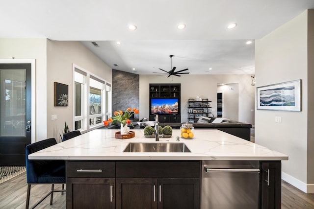 kitchen featuring sink, dark brown cabinets, a kitchen island with sink, and a breakfast bar area