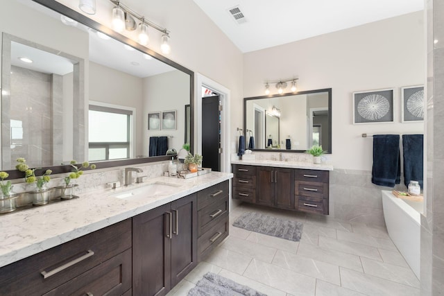 bathroom featuring vanity, tile walls, tile patterned flooring, and a bathing tub