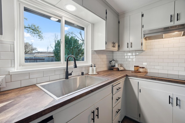 kitchen featuring white cabinetry, sink, butcher block counters, backsplash, and cooktop