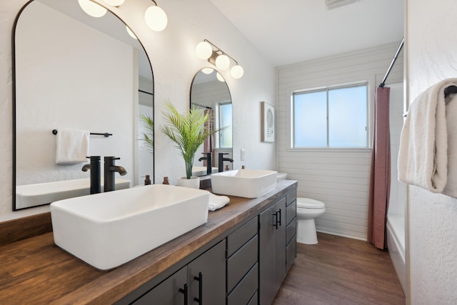 full bathroom with hardwood / wood-style flooring, shower / bathtub combination, vanity, and toilet